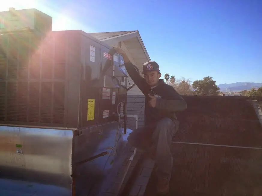 HVAC technician performing HVAC Inspection on a rooftop unit in Monee