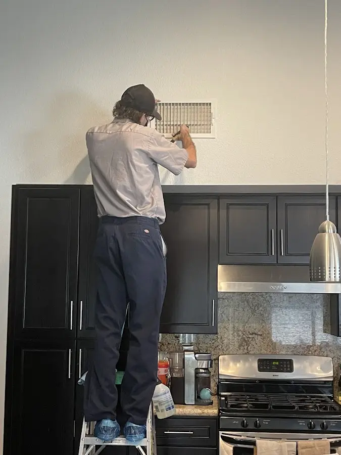 Technician inspecting an air vent during HVAC service in Monee